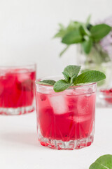 Cranberry drink with ice and mint on a white background.