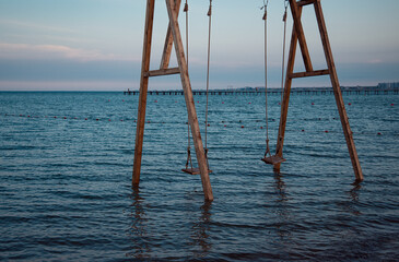 Wooden swing in the open ocean in dark blue. Place of rest and relaxation.