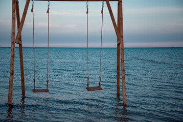 Wooden swing in the open ocean in dark blue. Place of rest and relaxation.