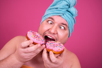 Funny guy eats pink donuts.