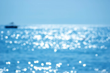 Soft focus bokeh light effects over a rippled, blue water background with lens flare and silhouette...