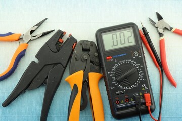 Multimeter and mounting tools on a color background close-up.