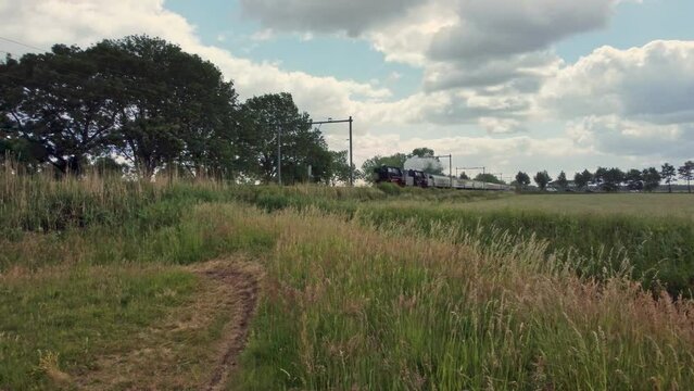 Steam Locomotive with lots of wagons driving through landscape in Soest area