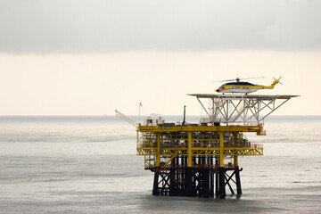 A helicopter on top of a offshore oil-platform transporting roughnecks to nearby rigs