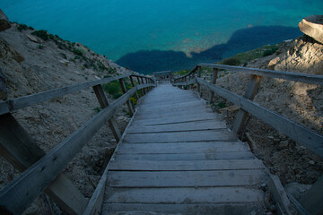 Naklejka premium Wooden staircase leading from the mountains to the sea. Paradise place for tourism and recreation. Hiking.