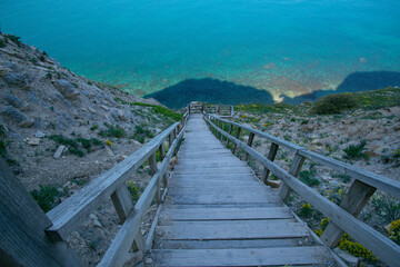 Obraz premium Wooden staircase leading from the mountains to the sea. Paradise place for tourism and recreation. Hiking.