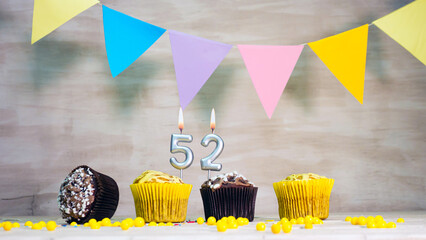 Birthday background with number 52. Beautiful birthday card with colorful garlands, a muffin with a...