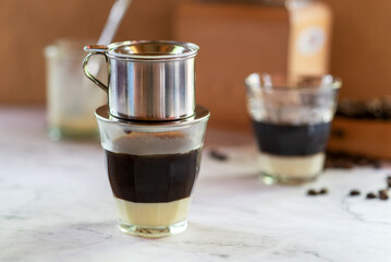vietnamese coffee, dark roast coffee brewing with Vietnamese drip filter in glass on sweet condensed milk.