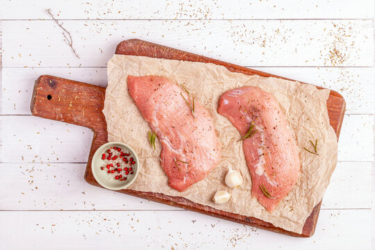 Two raw veal escalope on the old wooden cutting board, top view