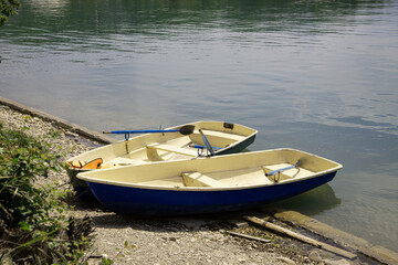 Two wooden boats with oars tied on the shore of the lake. Fishing and tourism.