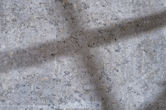 Rough concrete wall with the crossed shadows close up