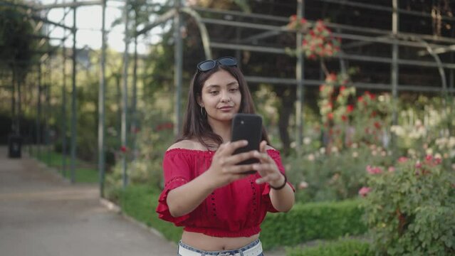 a young girl taking selfies with her phone in a beautiful park