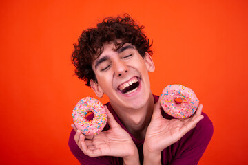 Funny guy eats pink donuts.