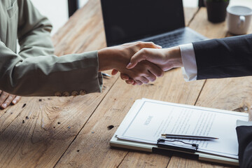 Managers and job applicants shake hands after the interview, resumes are important documents for job application. It should contain resume, training history, education, talent, work skills, etc.