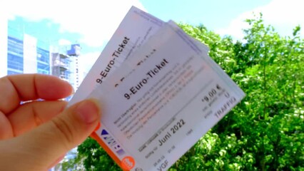 Frankfurt - June 2022: female hands hold three 9-euro travel subscription, monthly travel passes in germany for public transport in june, travel concept for country, in german: 9 euros - ticket