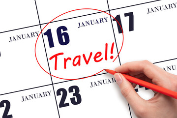 Hand drawing a red circle and writing the text TRAVEL on the calendar date 16 January. Travel planning.