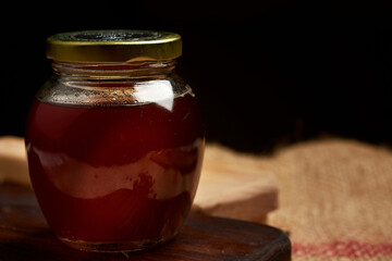 Honey produced by bees placed on a cutting board, in the background a jute bag made of natural fiber