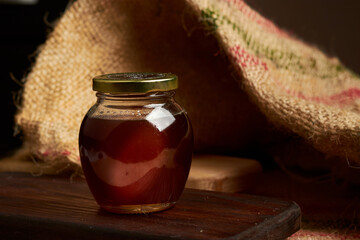 Honey produced by bees placed on a cutting board, in the background a jute bag made of natural fiber