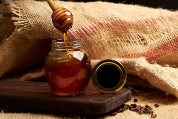 Honey produced by bees, using a wooden server and placed on a cutting board, in the background a...