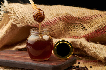Honey produced by bees, using a wooden server and placed on a cutting board, in the background a...