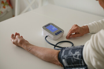 Hands of a woman taking her blood pressure - obrazy, fototapety, plakaty