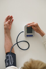 Hands of a woman taking her blood pressure