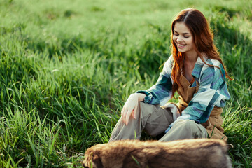 Woman happily smiling at playing with her little dog outdoors on fresh green grass in the summer sunshine her and her dog's health, Health Concept and timely treatment for insects ticks and tick fleas