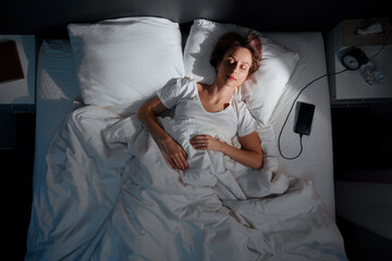 Top view of Young Woman Sleeping Cozily on a Bed in Bedroom at Night.