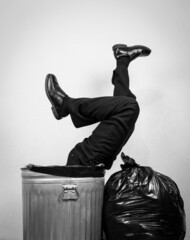Businessman in Suit Stuck in Trash Can With Legs Sticking Out. Concept of Over a Barrel. Being...