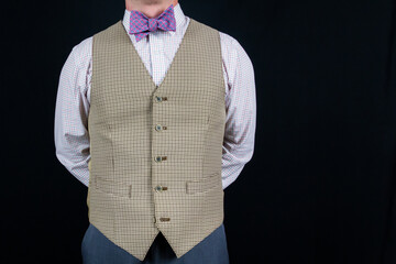 Portrait of Gentleman in Vest and Bow Tie Holding Hands Behind Back. Vintage Style and Retro Fashion.