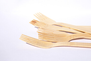 Wooden eco bamboo cutlery forks on bright white background. Meal time concept