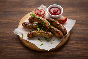 Sausages fried with  herbs, selective focus wooden board