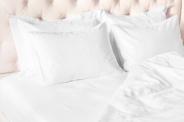 White pillows, duvet and duvet case on bed with beige headboard.