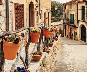 View of the ancient streets of Valldemossa. violets in clay pots on the hedge