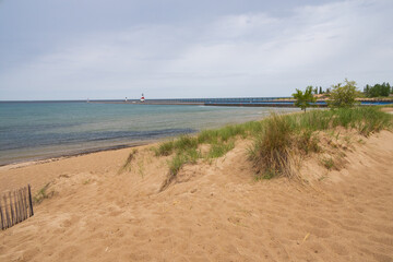 Fototapeta na wymiar Sand beach and beachgrass with St. Joseph North Pier Inner Lighthouse and St. Joseph North Pierhead Outer Lighthouse, Michigan in background