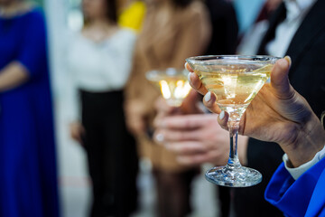 Champagne in a martini glass, a girl holding an alcoholic beverage in her hand, celebrating an event at a party.