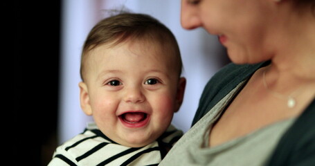 Happy smiling baby in mother arms. Parent holding adorable cute child smile