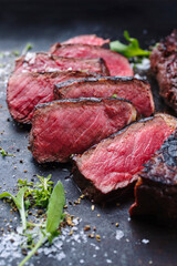 Barbecue dry aged wagyu roast beef steak with lettuce and spice served as close-up on a rustic black board