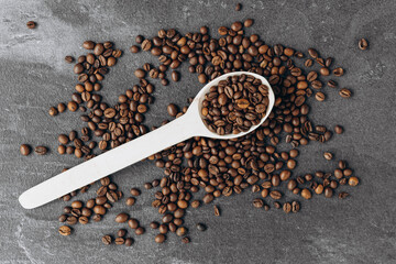 Coffee beans on wooden spoon isolated on dark background