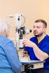 A male ophthalmologist checks the eyesight of an adult woman using a modern device with a light beam