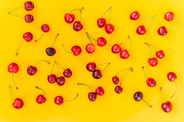 Cherry pattern. Flat lay of cherries on a yellow background.Top view