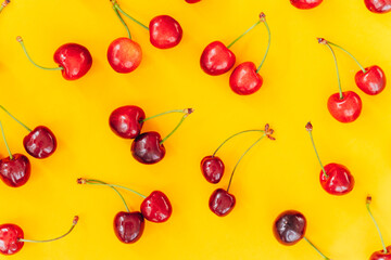 Naklejka na ściany i meble Cherry pattern. Flat lay of cherries on a yellow background.Top view