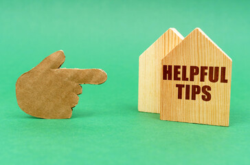 On a green surface, a hand points to a house with an inscription - Helpful Tips