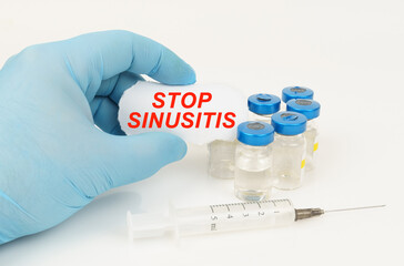 In his hand is a piece of paper with the inscription - STOP SINUSITIS, next to it lies a syringe...