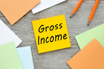 Gross income , text on orange sticky note on wooden background