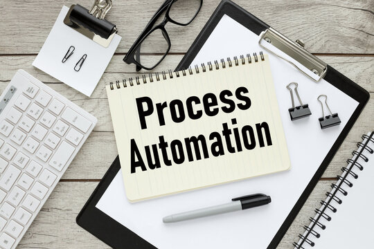 PROCESS AUTOMATION. wooden table and folder. text on white notepad paper.