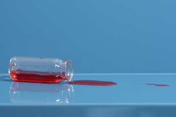 .Red liquid spilled on the table from an overturned glass vial