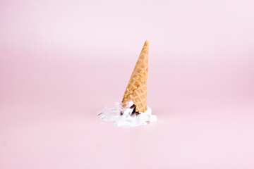 Melting ice cream with waffle cone on pastel color backgrounds. Summer creative food concept.