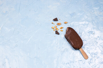 Broken chocolate ice cream bar with sticks. Chocolate popsicles with nuts on pastel blue...