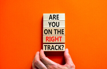Right track symbol. Concept words Are you on the right track on wooden blocks on a beautiful orange table orange background. Businessman hand. Business motivational and right track concept.